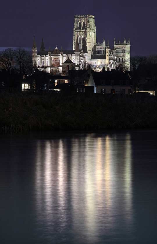 The cathedral illuminated at night and reflected in the River Wear.